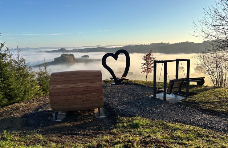 Viewpoint near Cobbenrode with heart sculpture, wooden lounger and swing above misty Sauerland valleys