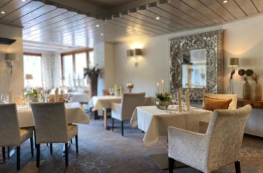 Restaurant at Hotel Hennemann with laid tables, upholstered chairs and a large ornate mirror