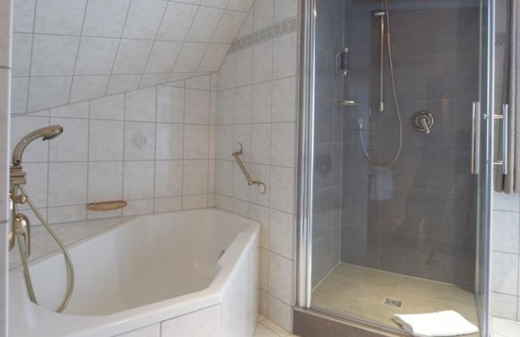 Bathroom of the comfort double room with corner bath and glass shower cubicle under the sloping roof