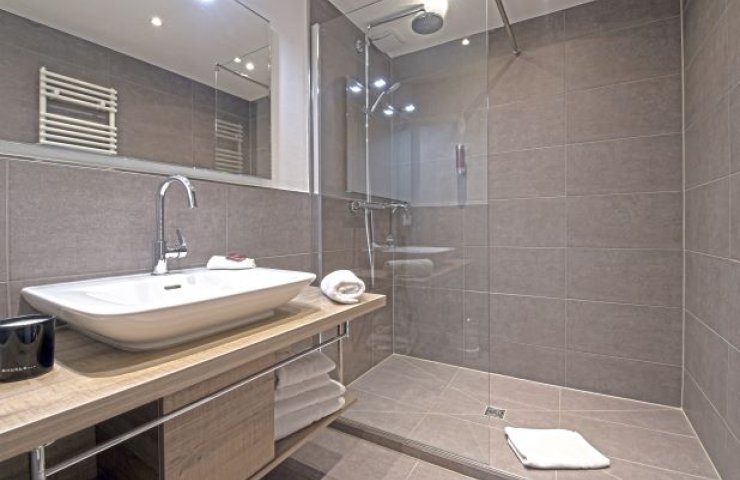 Modern bathroom with walk-in glass shower, countertop basin on a wooden vanity and a large mirror