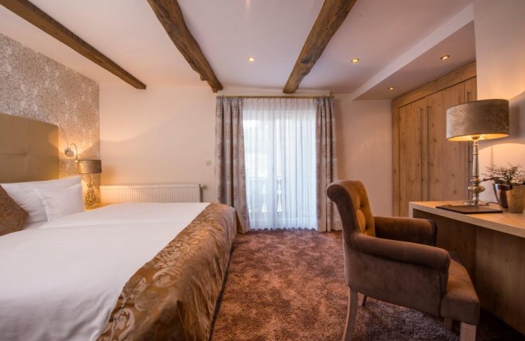 Standard double room with wooden beams, double bed, desk and balcony door